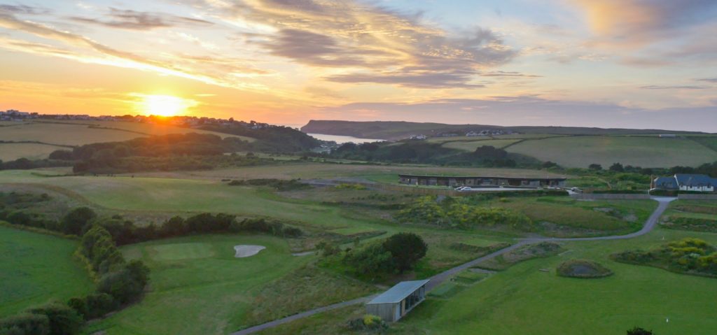 Things to do in Polzeath Cornwall: Sun setting over sea beyond golf course at The Point at Polzeath