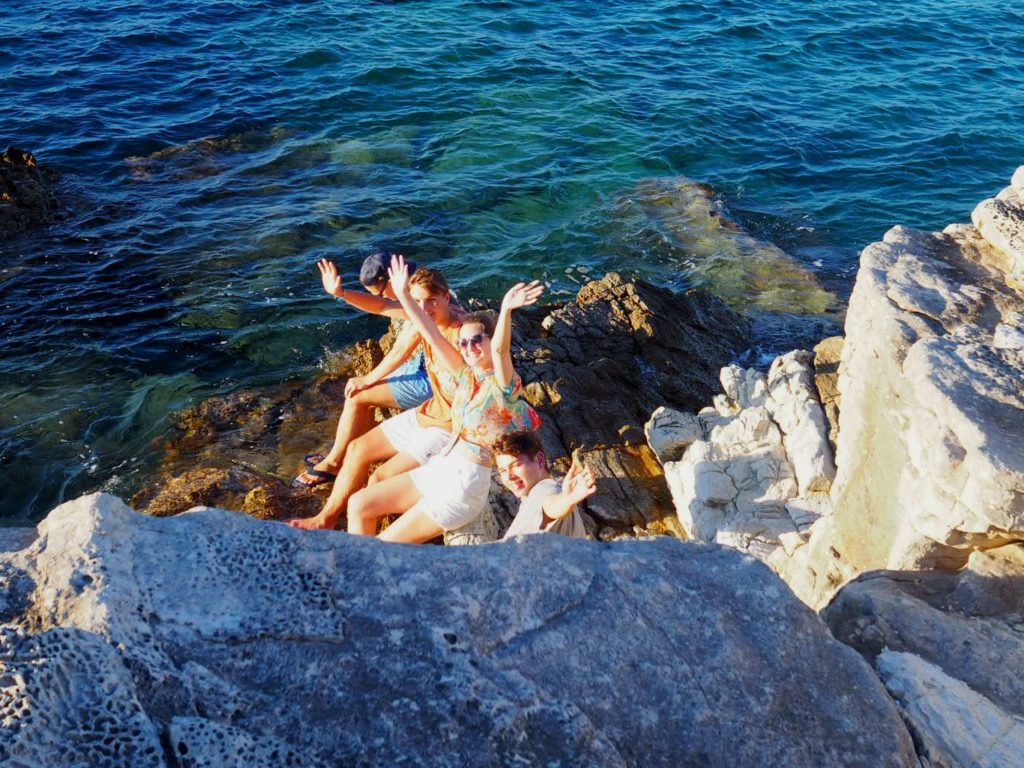 Friends waving from rocks at water's edge in Gaios. Copyright©2017 mapandfamily.com 