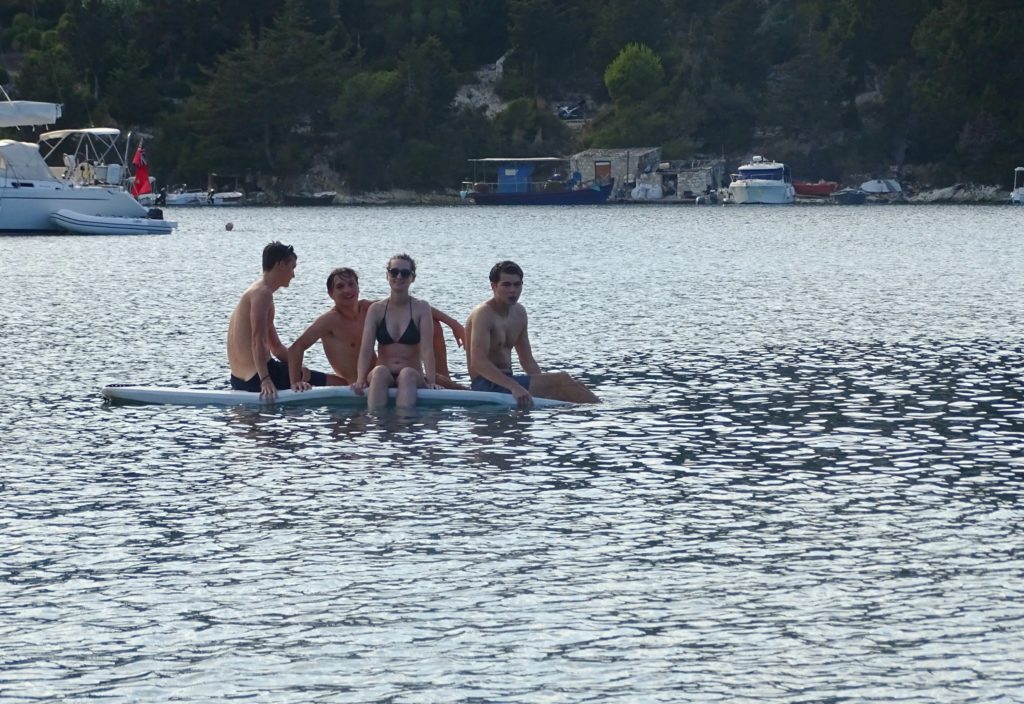 Four people sitting on paddle board at Morgonissi beach, Paxos. Copyright©2017 mapandfamily.com 