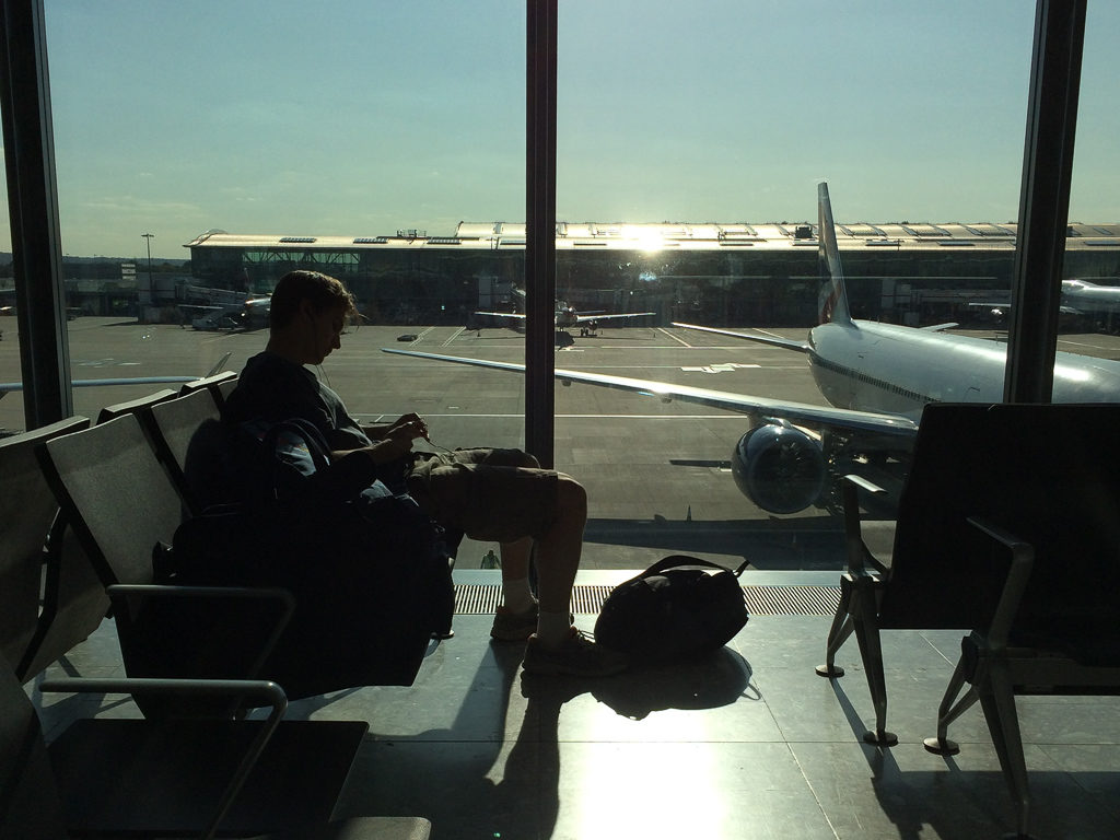 Silhouette of boy sitting at departure gate in airport. Interrail packing list. Copyright©2018 mapandfamily.com 