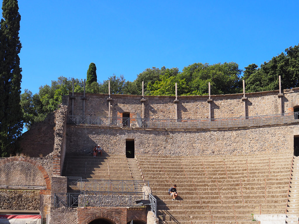 Tiered seating in a stone open air theatre in Pompeii. Copyright©2019 mapandfamily.com