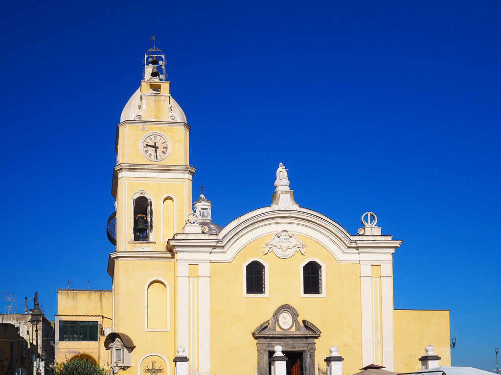 Pretty lemon painted church on Procida island, with bell tower against deep blue sky. Copyright©2019 mapandfamily.com 