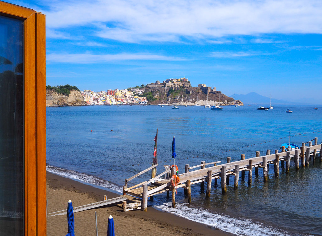 View from window of Conchiglia restaurant on Chiaia beach, Procida to Corricella across the bay. Copyright©2019 mapandfamily.com 