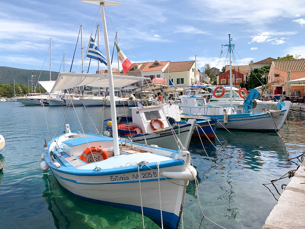 Kefalonia holidays: small blue and white boats in Fiscardo harbour. Copyright ©2019 mapandfamily.com 