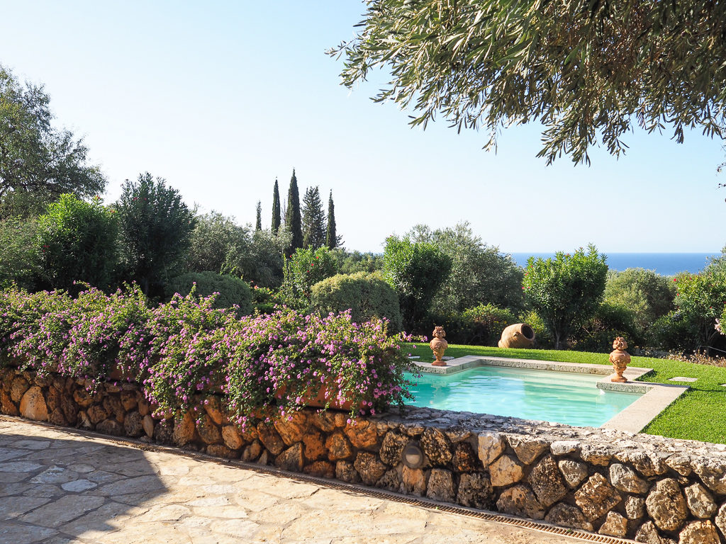 Kefalonia villa with pool. View from terrace to pool with terracotta urns, cypress trees and the sea. Copyright ©2020 mapandfamily.com