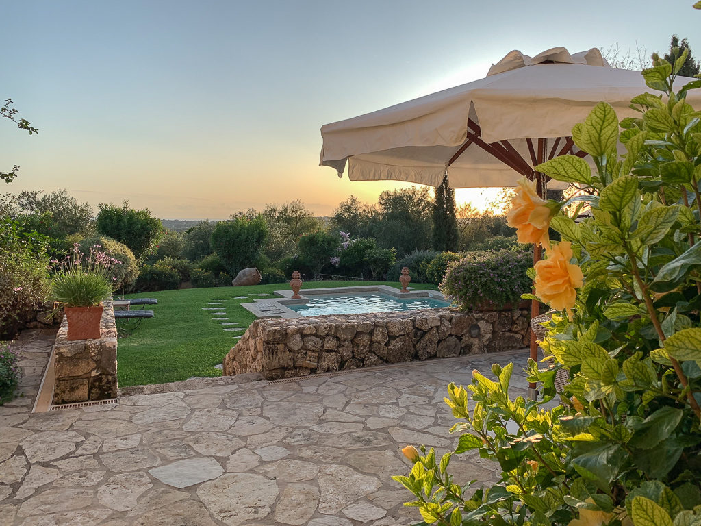 Villa in Kefalonia with pool. Terrace overlooking pool with yellow flowers and sun umbrella. Copyright ©2020 mapandfamily.com