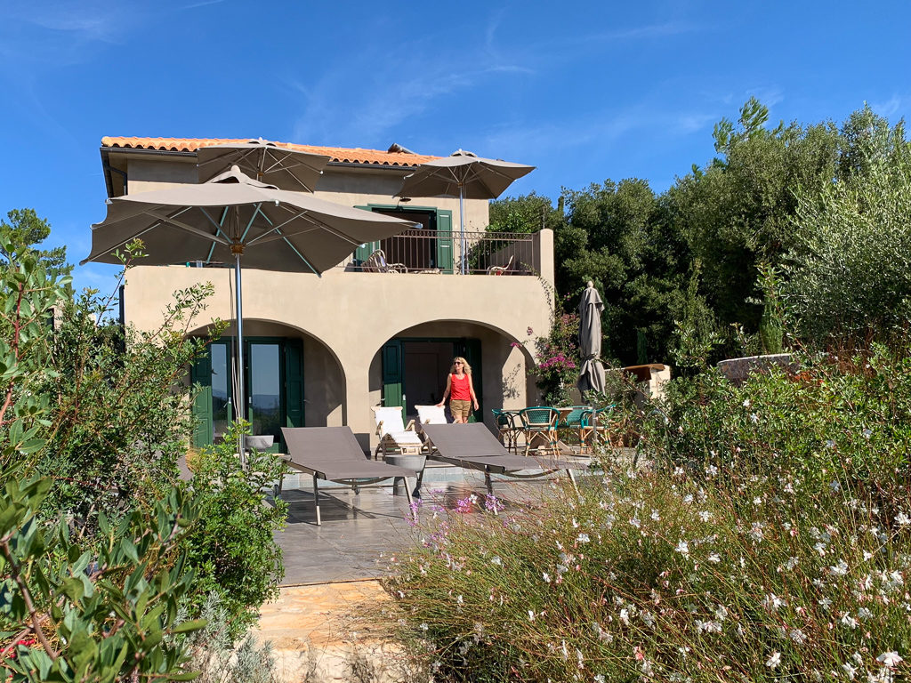 Fiscardo villas, exterior view of Fiscardo Bay Villa showing sunloungers and umbrella. Copyright ©2020 mapandfamily.com 