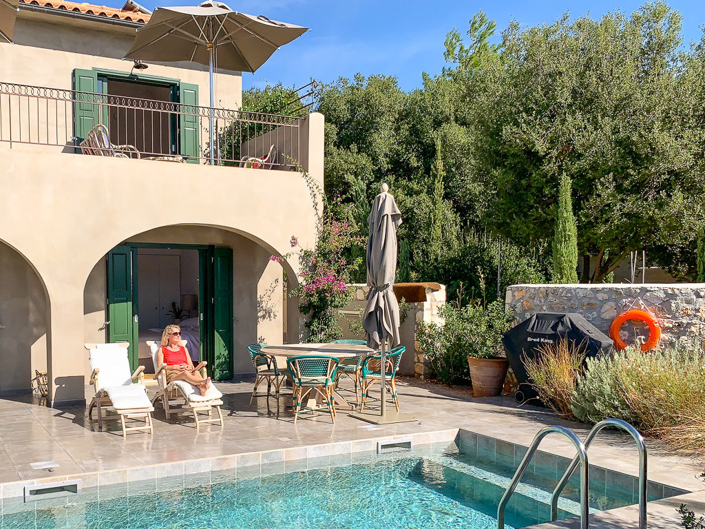 Luxury Greek villa. Woman in orange top sitting by plunge pool of Fiscardo Bay villa. Copyright ©2020 mapandfamily.com 