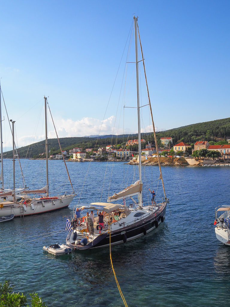 Fiscardo, yacht moored in bay. Houses on hillside in background 