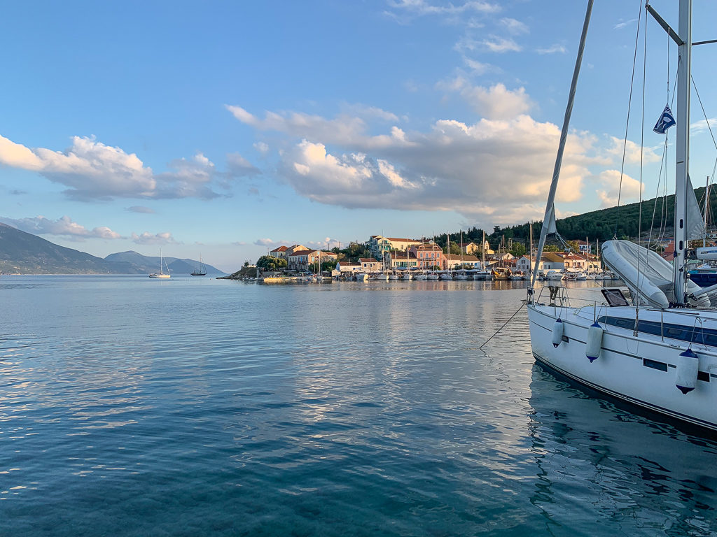 Fiskardo in Kefalonia, view of the harbour and boats at moorings in the evening light. Copyright ©2020 mapandfamily.com 