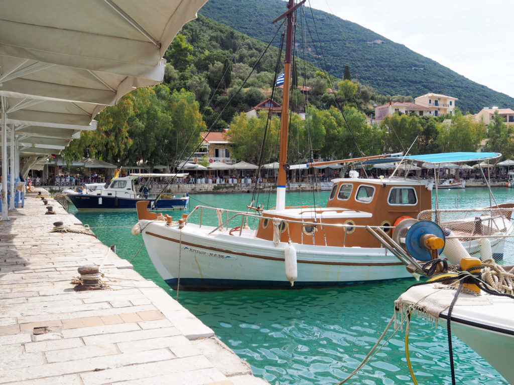 Vasiliki Lefkada. Wooden boat moored at the quayside with trees in the background. Copyright@ 2022 mapandfamily.com 