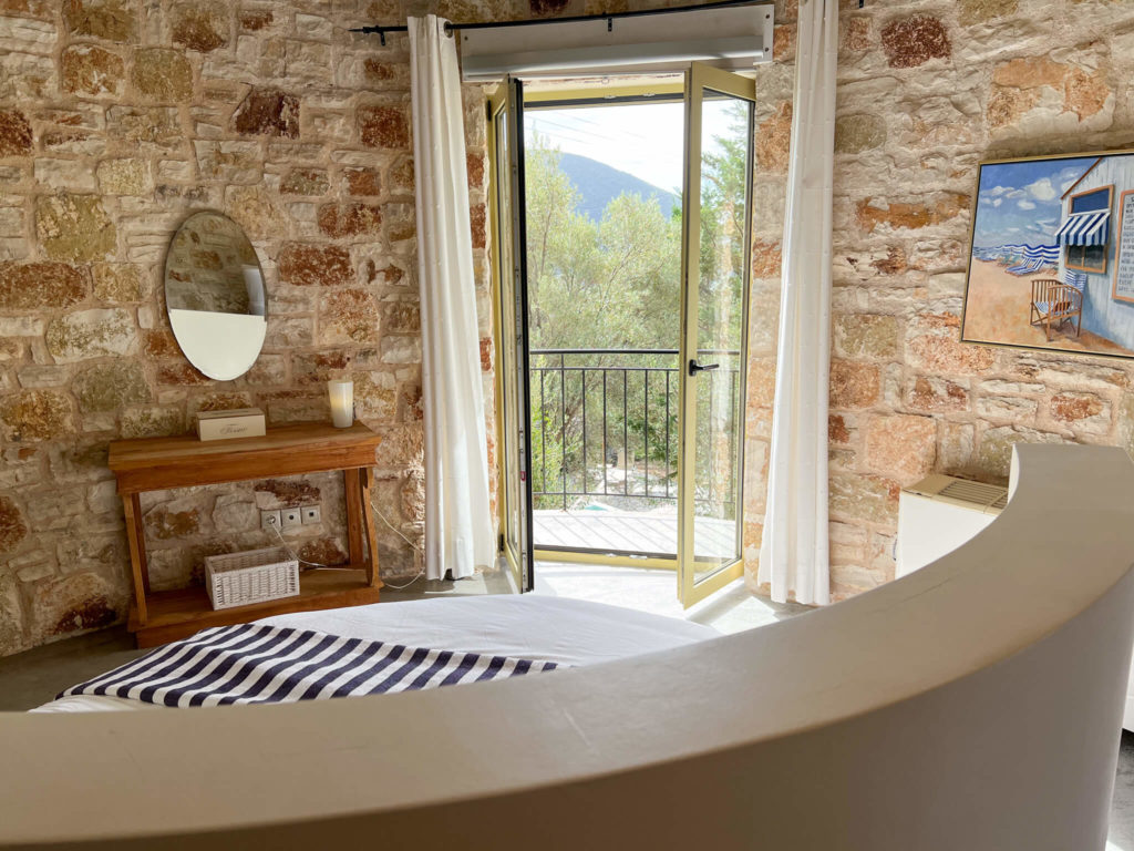 Circular bedroom in Thimari villa in Vasiliki with doors open to balcony. Copyright@ 2022 mapandfamily.com 