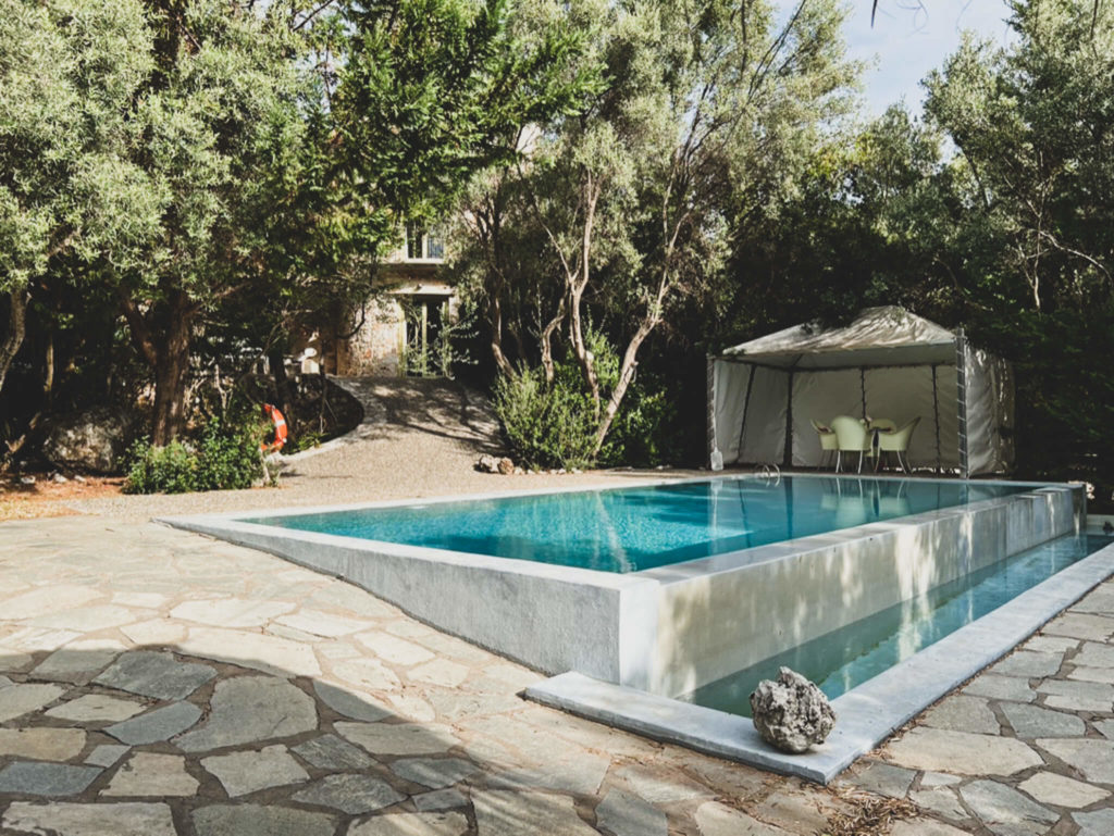 Pool in garden of Thimari villa in Vasiliki, Lefkada. Turquoise water and table and chairs under awning. Copyright@ 2022 mapandfamily.com 