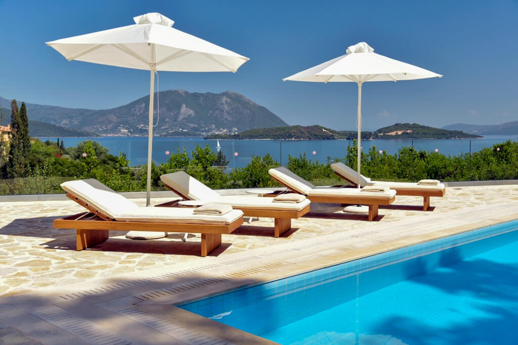 Meganisi villa: white parasols and sunbeds on terrace with sea view. Copyright@ 2022 reserved to photographer via mapandfamily.com