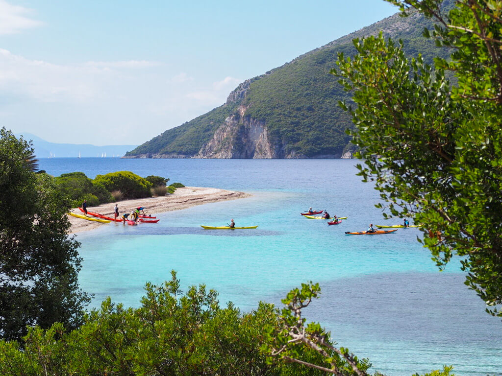 Things to do on Meganisi: kayakers landing at a beach. Copyright@ 2022 mapandfamily.com