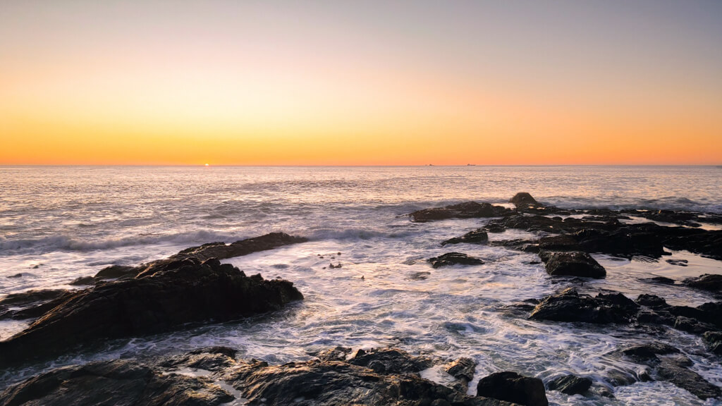 View of the gold and orange coloured sky at sunset on Atlantic seaboard, a romantic thing to do in Cape Town for couples. Copyright@2023 reserved to photographer via mapandfamily.com