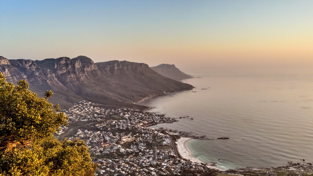 Pale golden sky above coast and mountain range at Cape Town. Copyright@2024 reserved to photographer via mapandfamily.com 