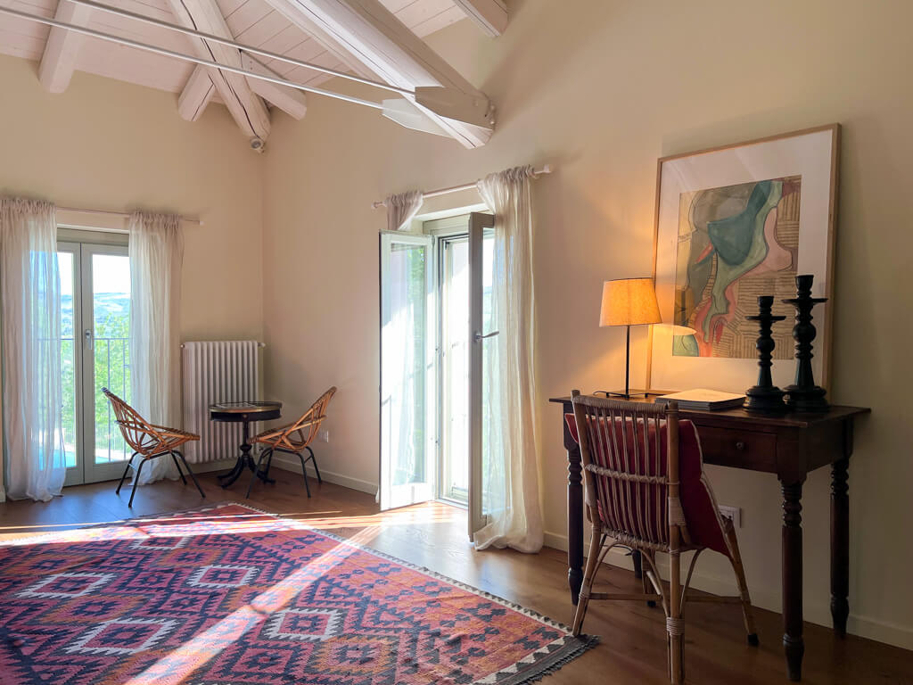 View of bedroom in Villa Giara showing desk and chair and kelim rug. Copyright@2023mapandfamily.com