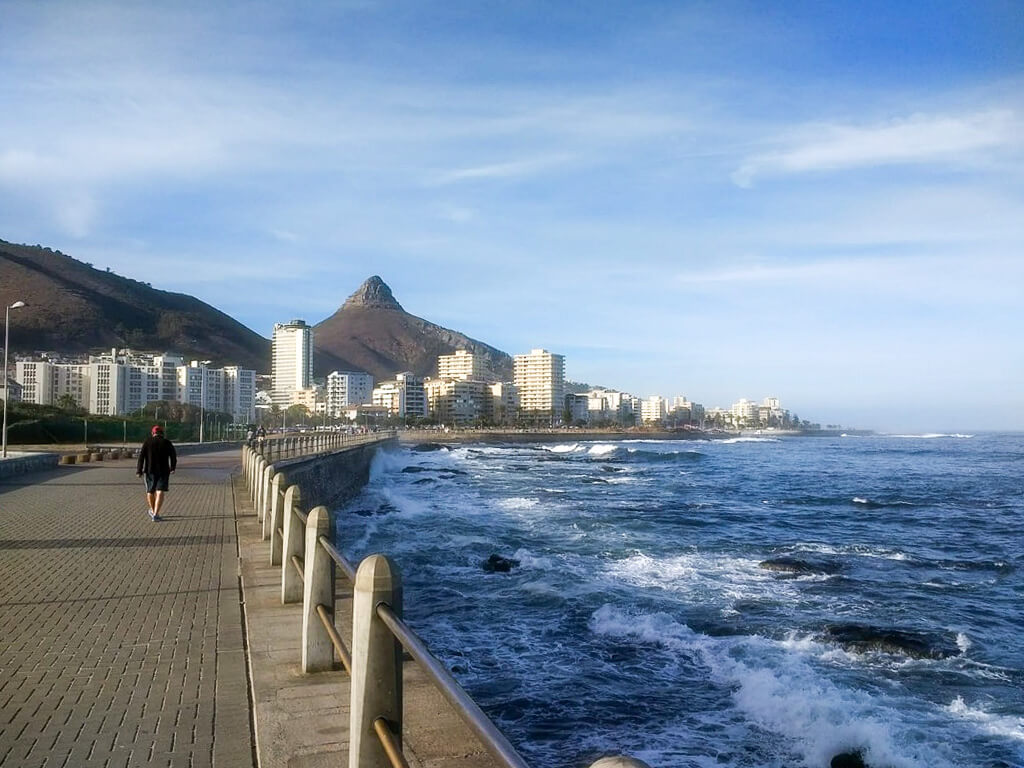 Things to do in Sea Point. Man walking on the promenade towards Lion's Head peak in the distance. Copyright@2023 reserved to photographer via mapandfamily.com 