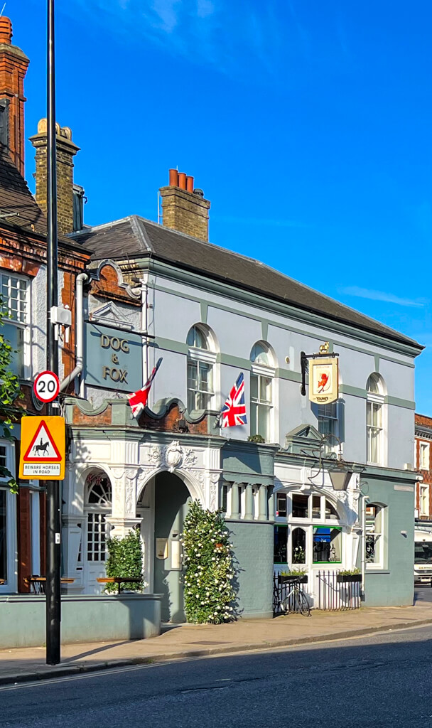 Exterior of Dog and Fox pub in centre of village with union flags hanging outside