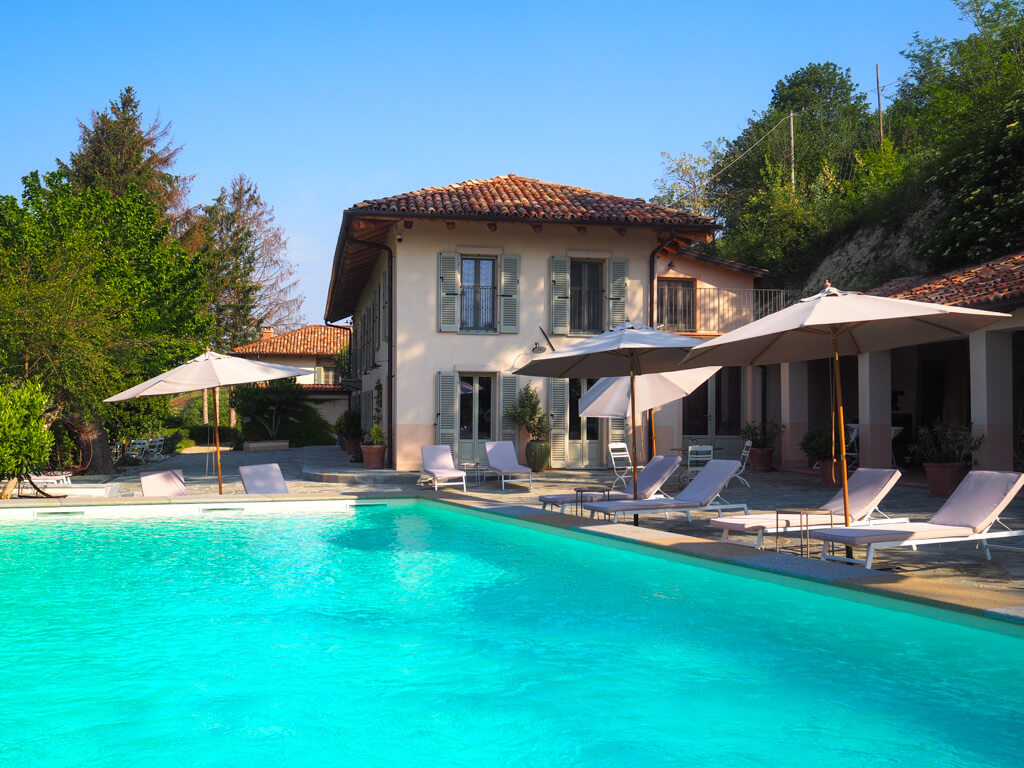 View of outdoor pool, sun loungers, parasols and portico at Villa Giara Bed and Breakfast in Calosso. Copyright@2023mapandfamily.com