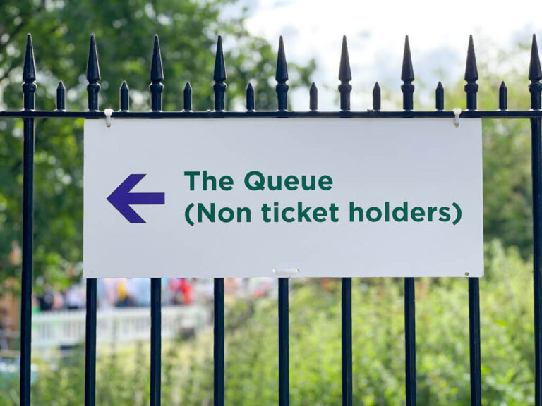 Official sign fixed to park railings showing direction of the Wimbledon Queue. Copyright@2023mapandfamily.com