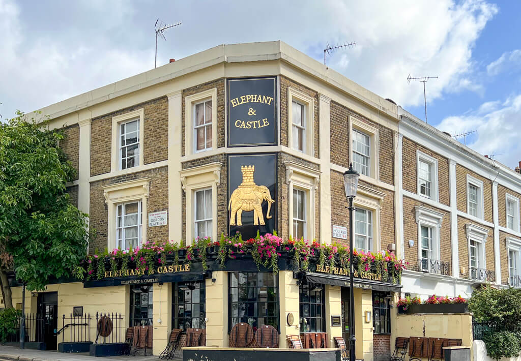 A historic pub called The Elephant and Castle with a golden sign depicting an elephant. Copyright@2023 mapandfamily.com