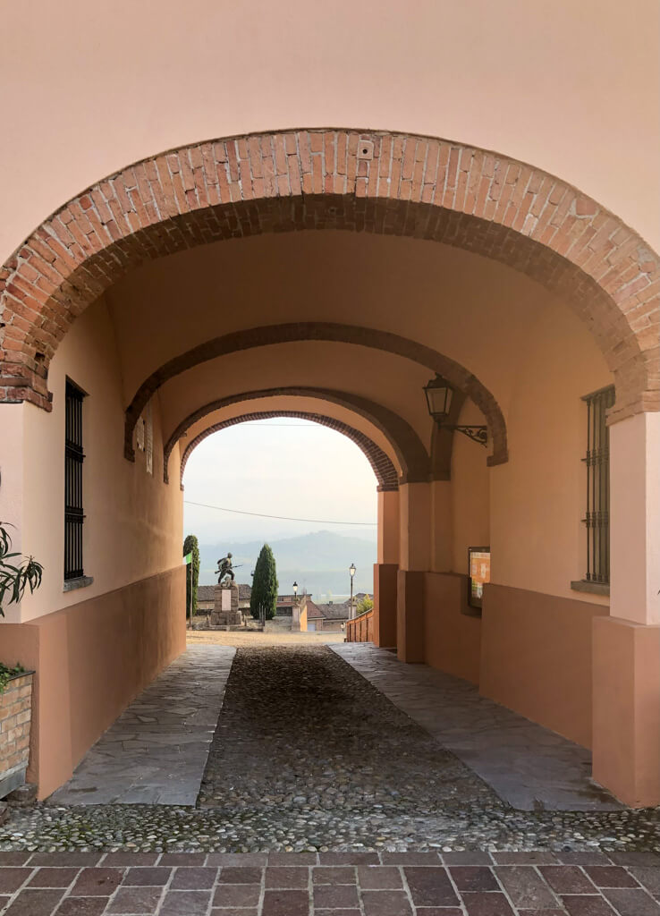 View of statue and distant mountains through archway in hilltop village. Copyright@2023 reserved to the photographer via mapandfamily.com