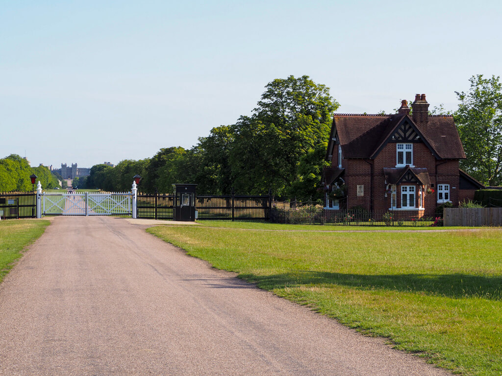 White gates across the Windsor Long Walk and a small brick built house with gable beside them. Copyright@2023 mapandfamily.com