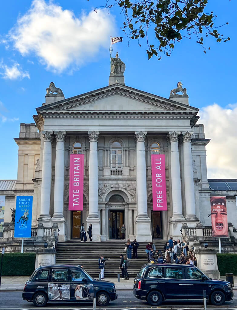 Columned exterior of Tate Britain with hanging reading: Free for All. Copyright@2023 mapandfamily.com