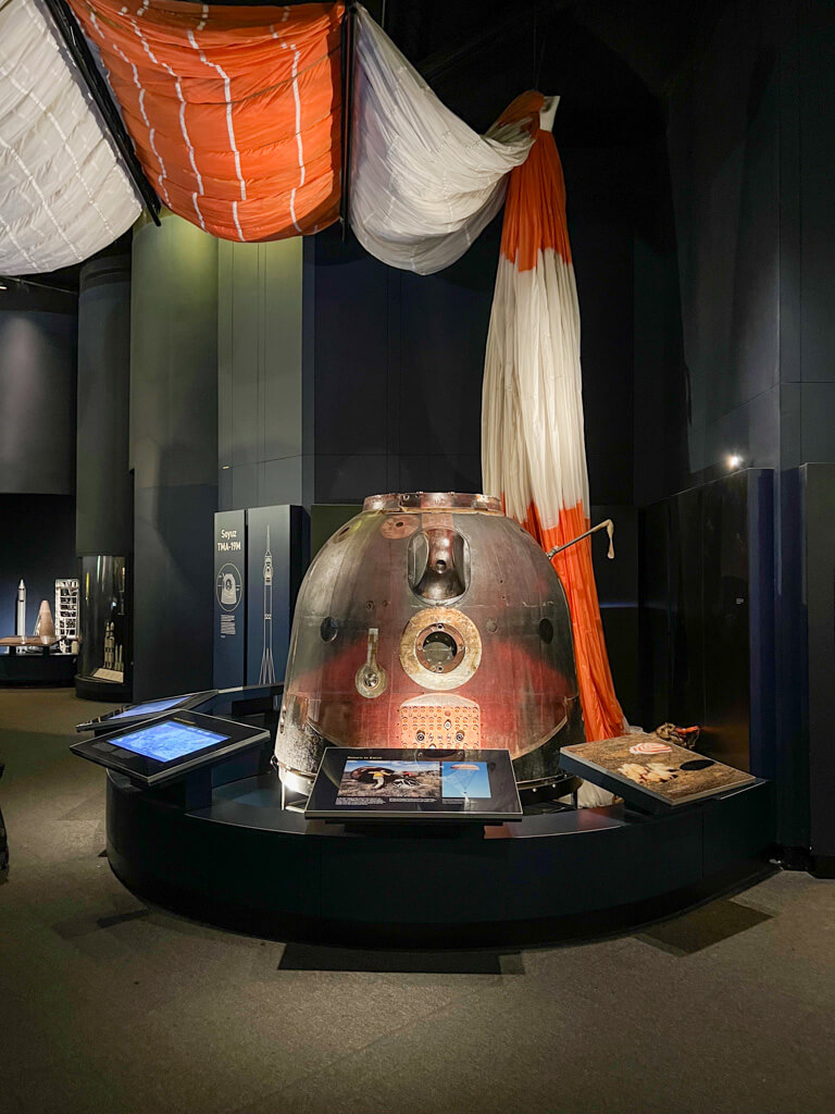 Orange and white parachute draped above a spacecraft. Copyright@2023 mapandfamily.com