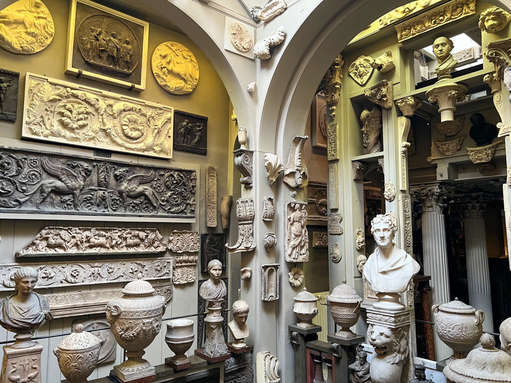 Interior of house with architectural plaques, busts and urns on every surface. Copyright@2023 mapandfamily.com