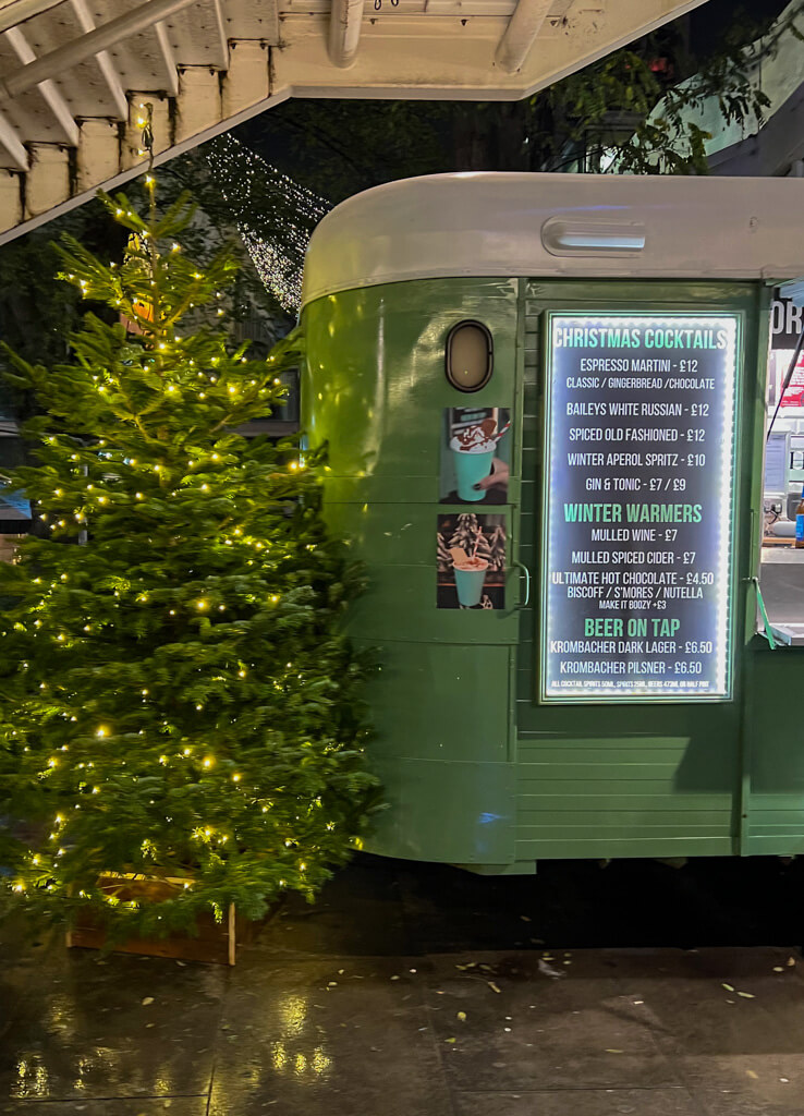 Christmas tree and cocktail menu on side of converted horsebox bar. Copyright@2023 mapandfamily.com