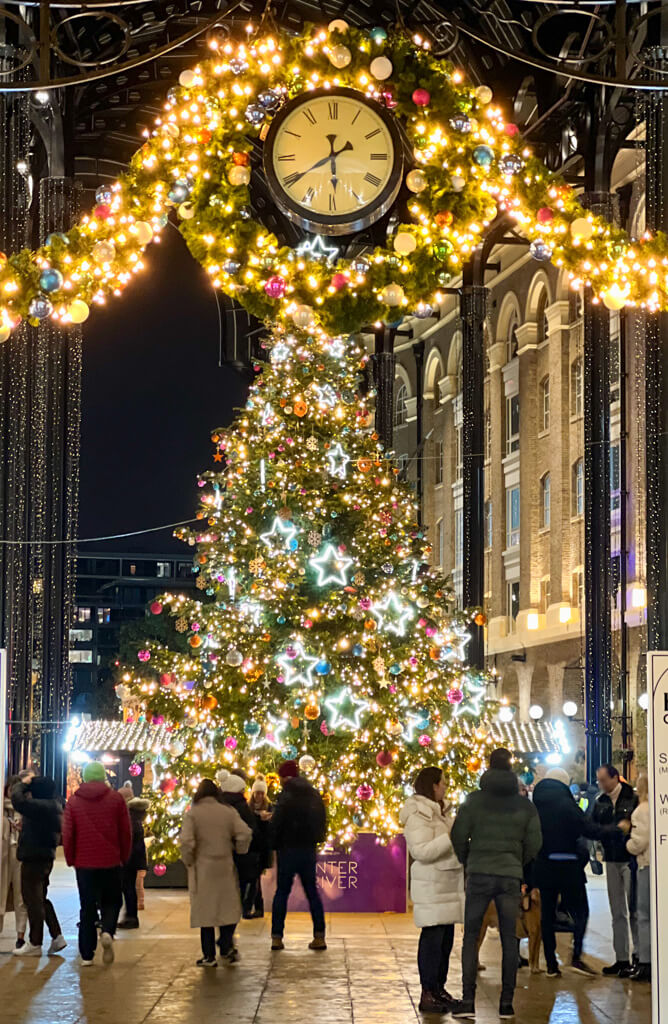 Colourful and brightly lit Christmas tree and suspended clock in Hay's Galleria. Copyright@2023 mapanfamily.com 