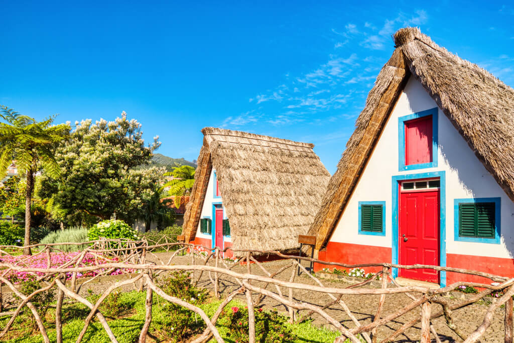 Traditional A framed houses with white walls and red and blue paintwork in Santana, Madeira