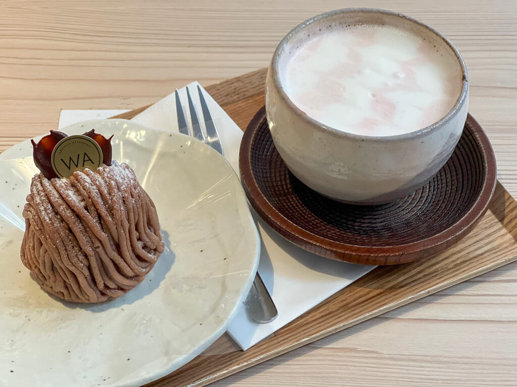 Tray with a Mont Blanc individual cake with chocolate decoration and latte with pink swirls. Copyright@2024mapandfamily.com 