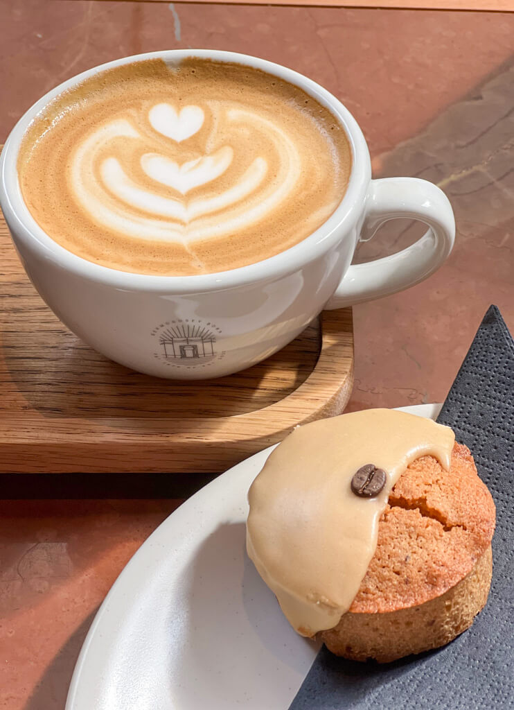 A cup of coffee on a wooden tray and iced cake on a plate. Copyright@2024mapandfamily.com 