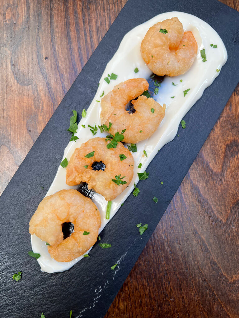 Prawns served on a black platter at Cent Anni Wimbledon. Copyright@2024 Nancy Roberts