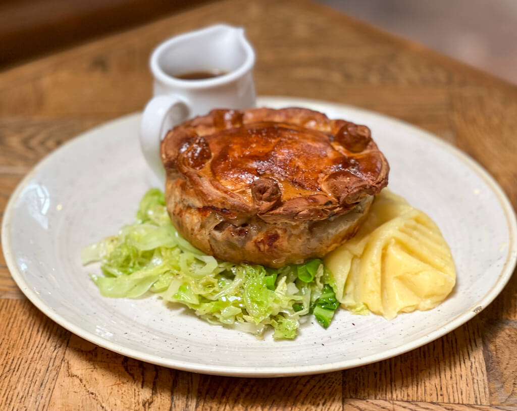 Homebaked pie with gravy and vegetables on a white plate. Copyright@2024 Nancy Roberts